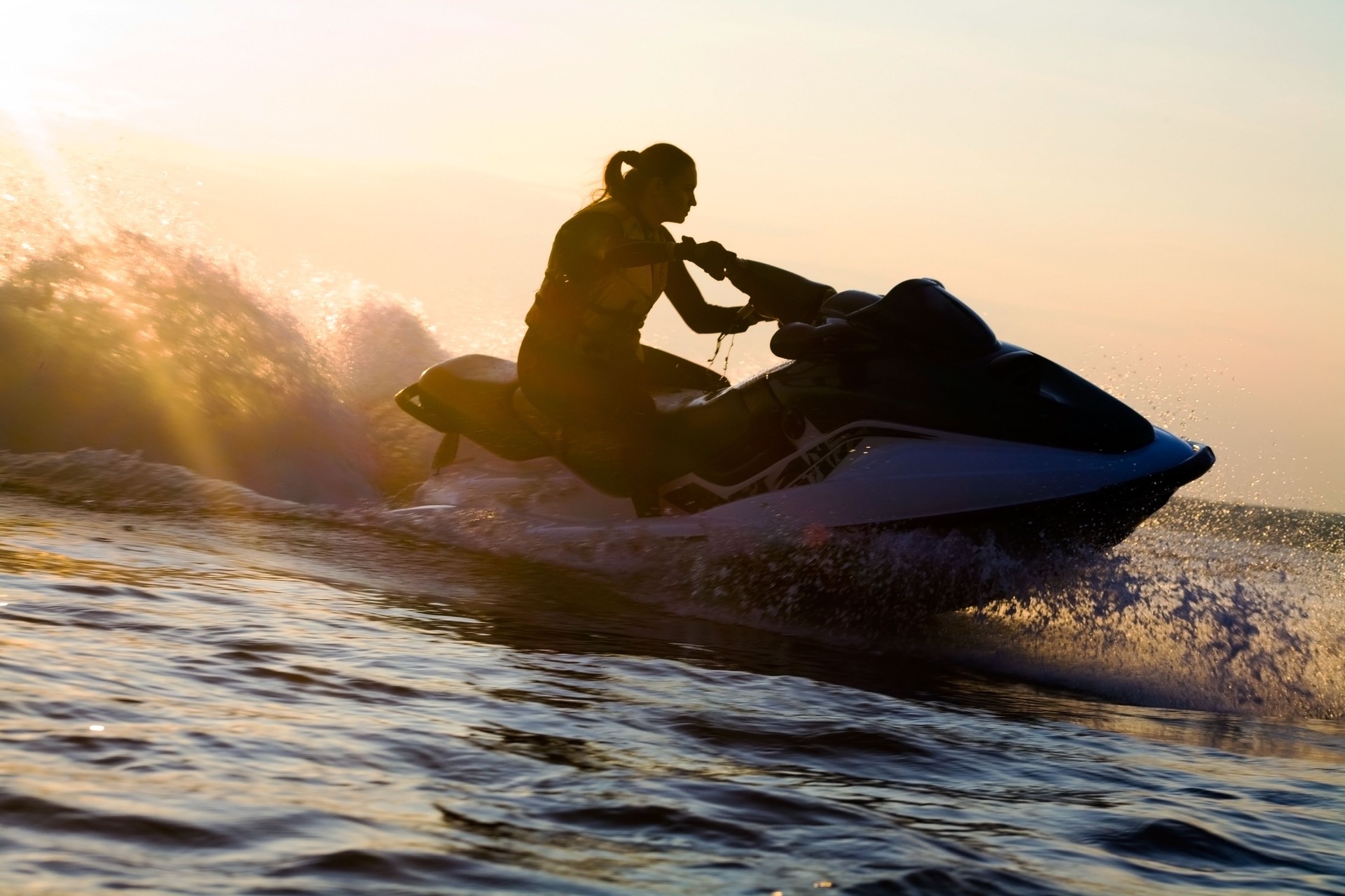 A beautiful girl riding a jet ski during sunset